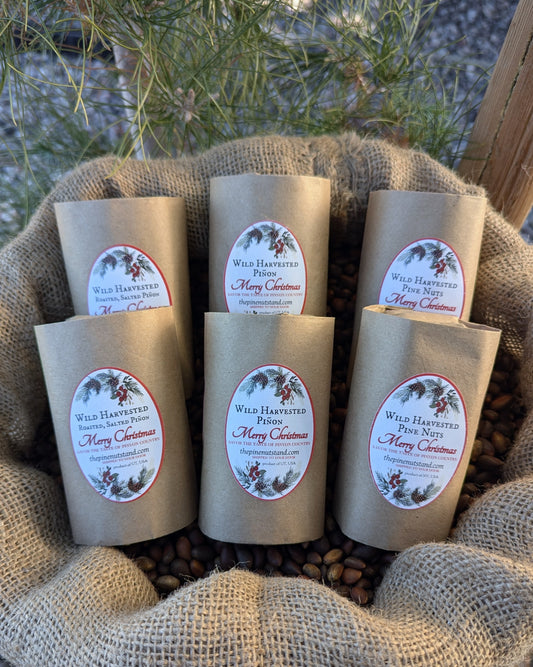 Bulk sack under coniferous close up with 2024 holiday packaging stocking stuffers variety pack pine nuts and roasted and raw pinon Christmas stocking stuffers.